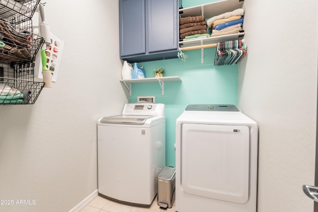 washroom with washing machine and dryer, cabinet space, light tile patterned flooring, and baseboards