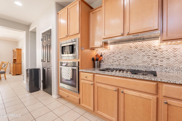kitchen with appliances with stainless steel finishes, under cabinet range hood, tasteful backsplash, light tile patterned floors, and crown molding