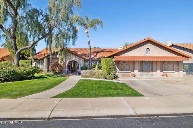 view of front of home with a tile roof, a front yard, stucco siding, and a chimney