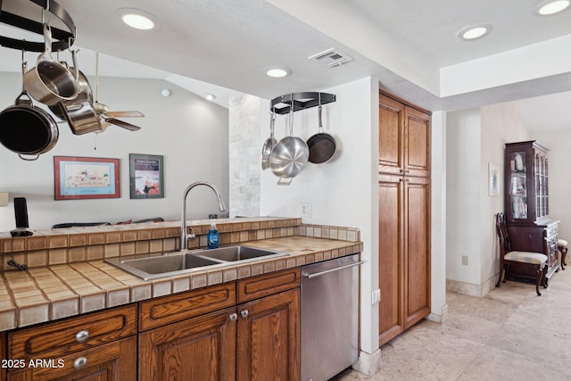 kitchen featuring a sink, stainless steel dishwasher, brown cabinets, tile counters, and recessed lighting