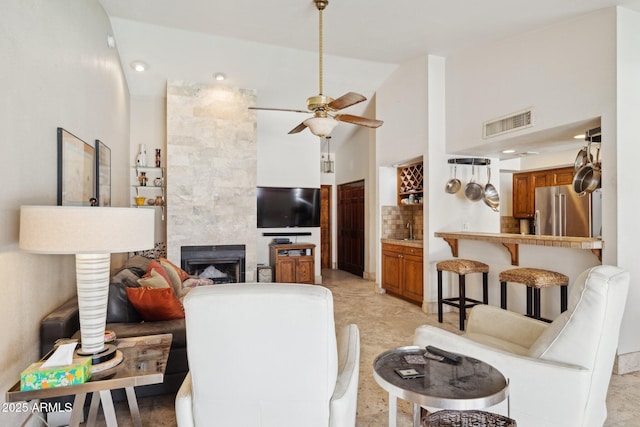 living area featuring ceiling fan, a towering ceiling, and a fireplace