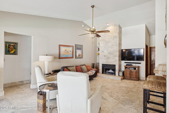 living room featuring vaulted ceiling, a ceiling fan, and a tiled fireplace