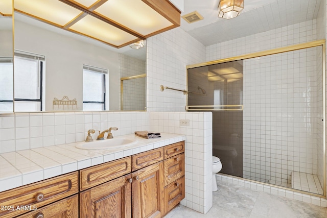 full bathroom featuring tile walls, a stall shower, toilet, and vanity