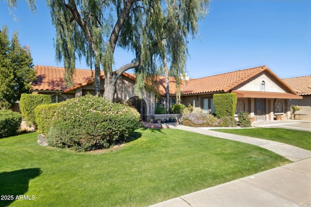 view of front of home with a tiled roof, a front yard, and stucco siding