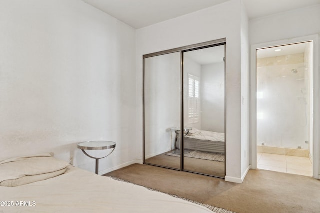 unfurnished bedroom with carpet floors, a closet, ensuite bathroom, and baseboards