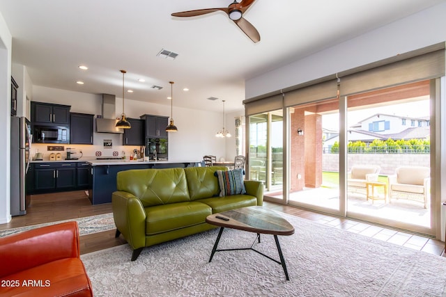 living room featuring ceiling fan with notable chandelier and light hardwood / wood-style floors