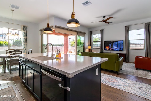 kitchen featuring dishwasher, ceiling fan with notable chandelier, sink, hanging light fixtures, and an island with sink