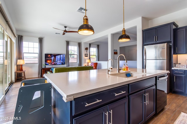 kitchen featuring sink, hanging light fixtures, black dishwasher, light stone counters, and a kitchen island with sink