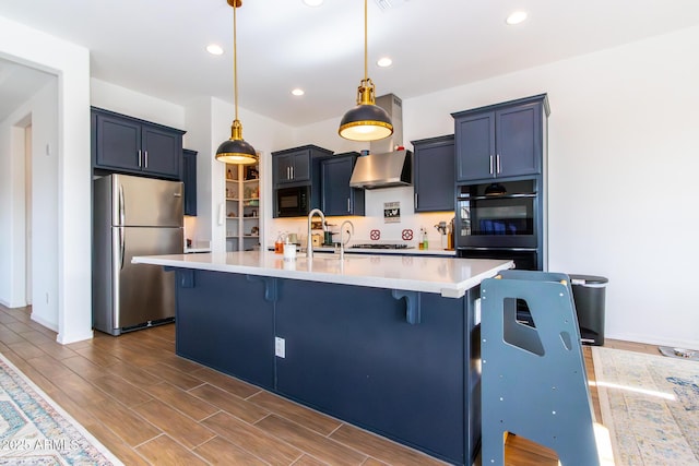 kitchen featuring a breakfast bar area, a kitchen island with sink, black appliances, and decorative light fixtures