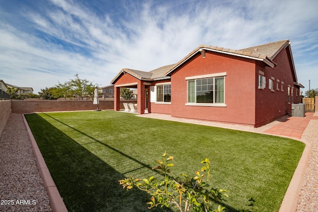 rear view of house with central AC unit, a patio area, and a yard