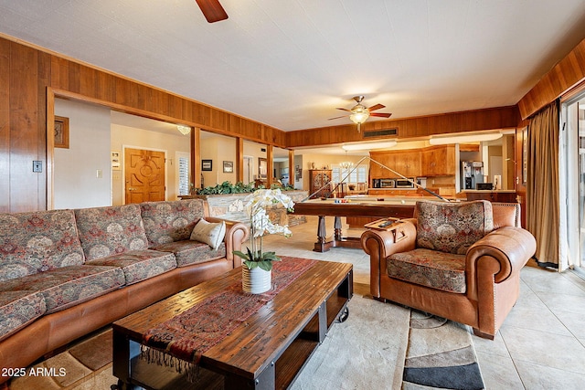 tiled living room with ceiling fan and wood walls