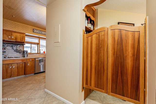 kitchen with stainless steel dishwasher, light tile patterned floors, black electric stovetop, and a textured ceiling