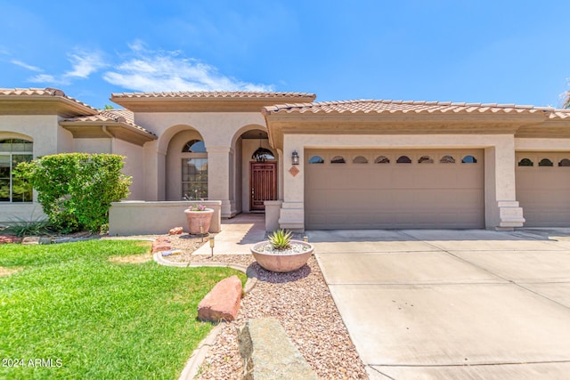 mediterranean / spanish house featuring a garage and a front lawn