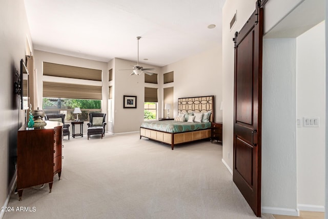 carpeted bedroom featuring a barn door, ceiling fan, and a towering ceiling