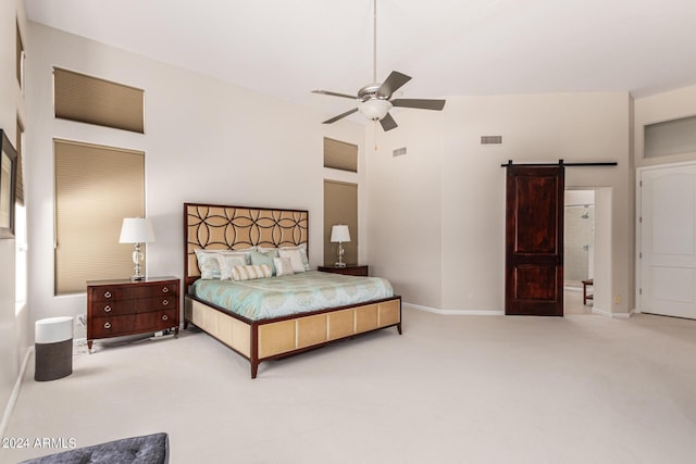 bedroom featuring ceiling fan, a barn door, carpet floors, and a high ceiling