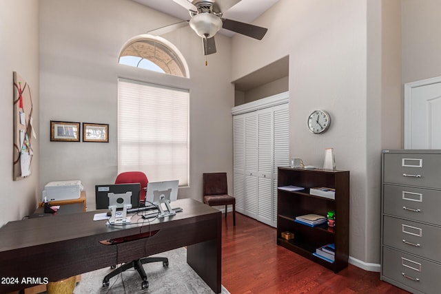 home office featuring ceiling fan, dark wood-type flooring, and a high ceiling