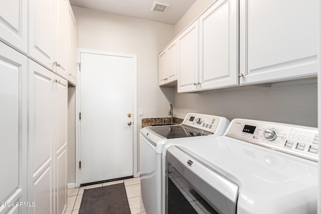 clothes washing area featuring washer and clothes dryer, light tile patterned floors, and cabinets