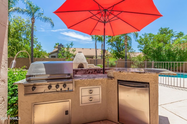 view of patio with a fireplace, a swimming pool, grilling area, and exterior kitchen