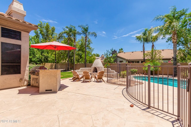 view of patio with an outdoor kitchen, a grill, a fenced in pool, and exterior fireplace