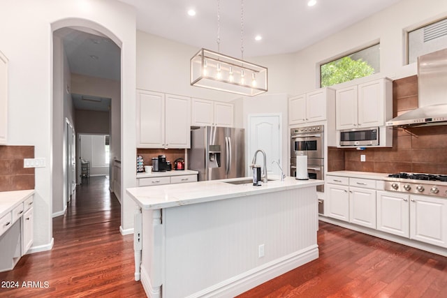 kitchen featuring decorative backsplash, appliances with stainless steel finishes, sink, hanging light fixtures, and an island with sink