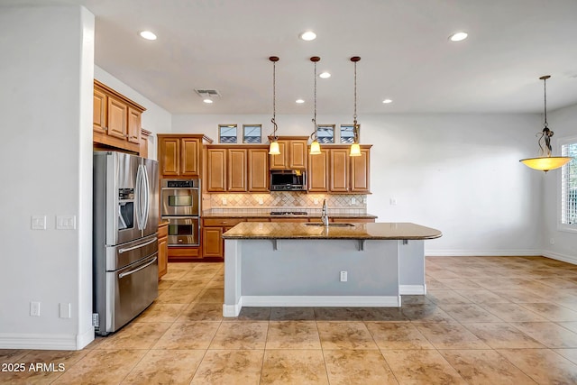 kitchen with sink, stainless steel appliances, pendant lighting, a breakfast bar area, and a center island with sink