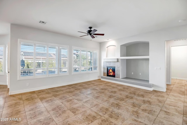 unfurnished living room featuring a fireplace, ceiling fan, and light tile patterned flooring