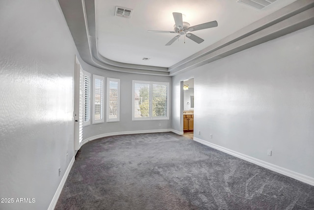 carpeted empty room featuring a tray ceiling and ceiling fan