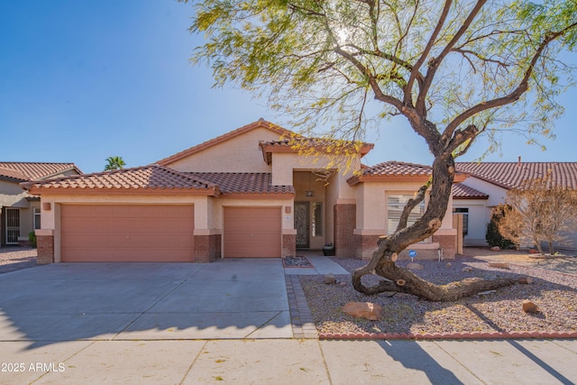 mediterranean / spanish-style home featuring a garage, concrete driveway, brick siding, and stucco siding