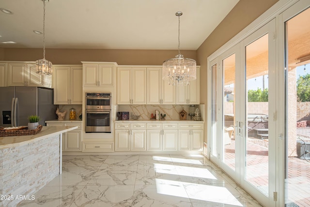 kitchen featuring appliances with stainless steel finishes, hanging light fixtures, marble finish floor, light countertops, and backsplash