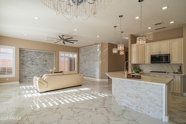 kitchen with marble finish floor, stainless steel microwave, gas cooktop, and a wealth of natural light