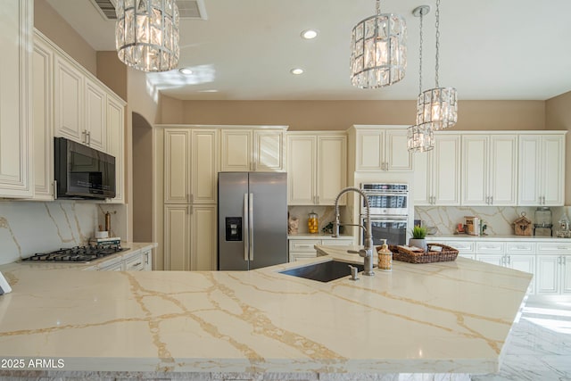 kitchen with appliances with stainless steel finishes, marble finish floor, a sink, and light stone counters