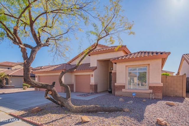 mediterranean / spanish home featuring an attached garage, brick siding, fence, driveway, and stucco siding