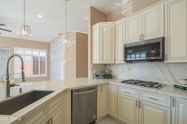 kitchen featuring light stone countertops, cream cabinets, appliances with stainless steel finishes, and a sink