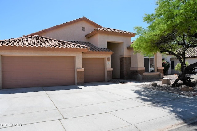 mediterranean / spanish home featuring an attached garage, driveway, a tile roof, and stucco siding