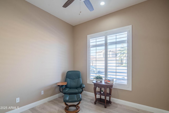 sitting room featuring light wood-style floors, baseboards, and a ceiling fan