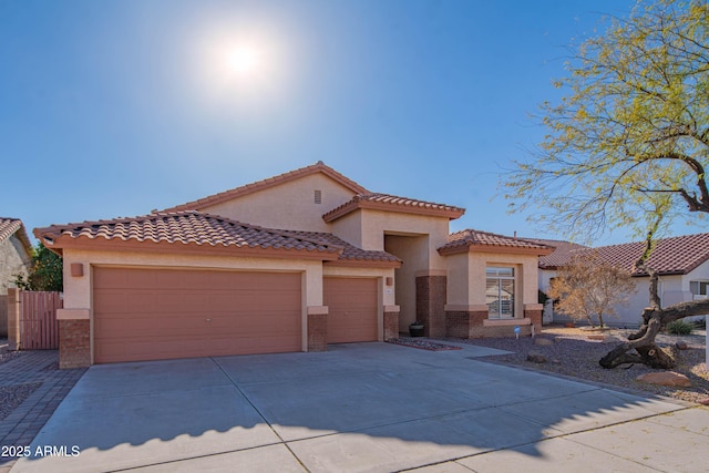 mediterranean / spanish house with driveway, brick siding, an attached garage, and stucco siding