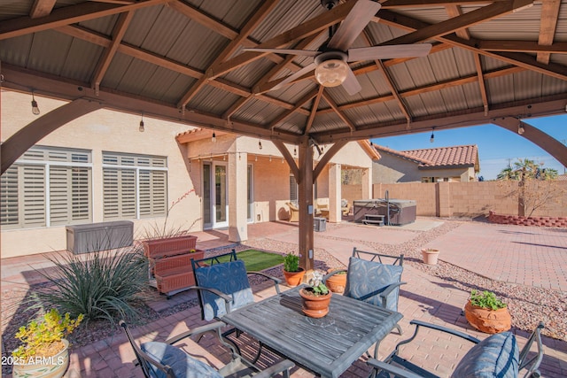 view of patio with a gazebo, fence, a ceiling fan, and a hot tub