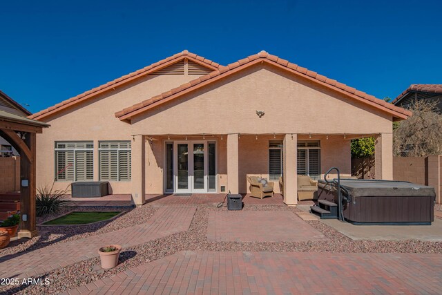 back of property with a patio, fence, french doors, stucco siding, and a hot tub