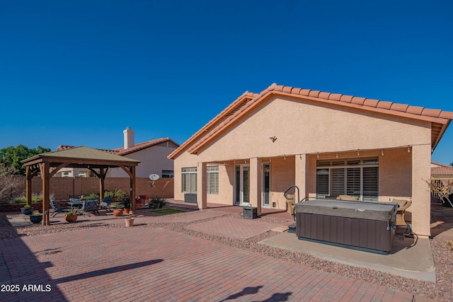 back of property with a patio, fence, a gazebo, stucco siding, and a hot tub