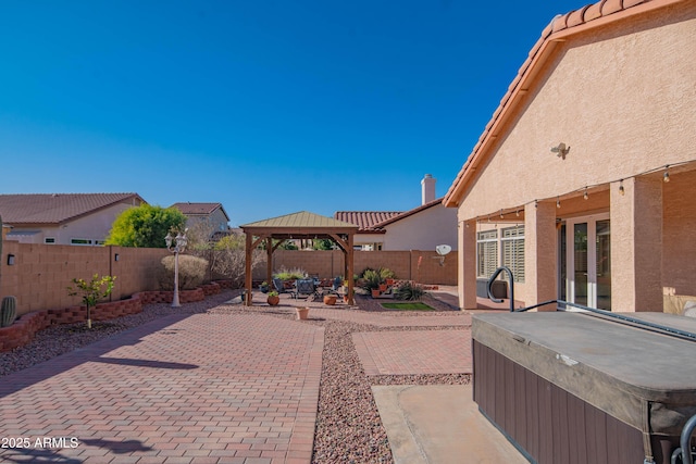 view of patio / terrace featuring a fenced backyard, a hot tub, and a gazebo