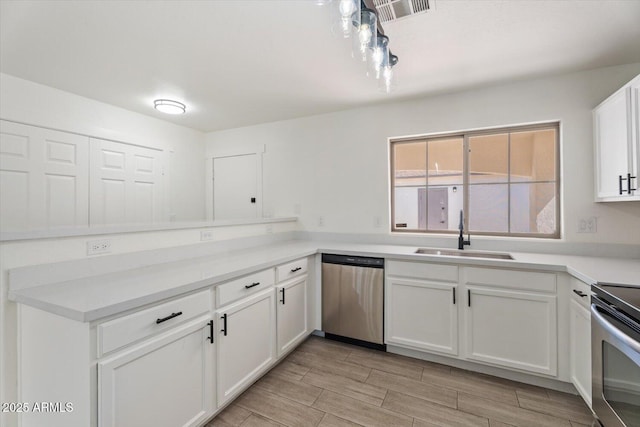 1510 W Fillmore St, Phoenix, AZ 85007 - kitchen featuring stainless steel appliances, white cabinets, light countertops, light wood-style floors, and a peninsula