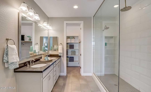 bathroom with tile patterned flooring, vanity, and a tile shower