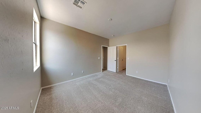 empty room with baseboards, visible vents, and carpet floors