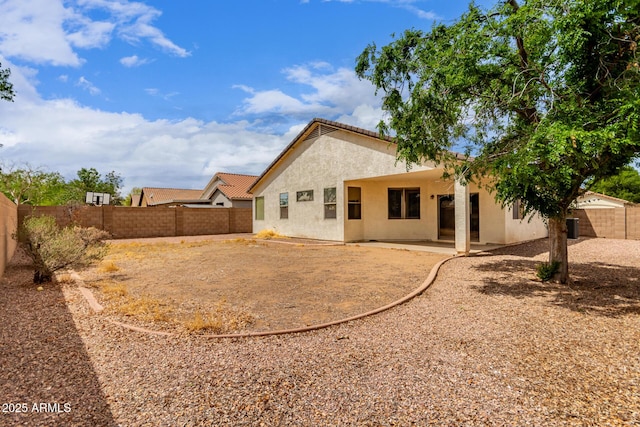back of house featuring a fenced backyard, a tile roof, stucco siding, and a patio