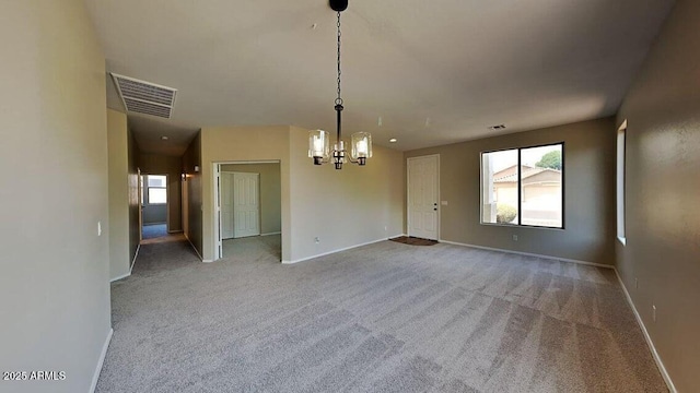 unfurnished room with carpet flooring, a wealth of natural light, and an inviting chandelier