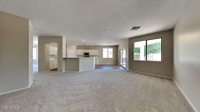 unfurnished living room featuring baseboards, visible vents, recessed lighting, and light carpet