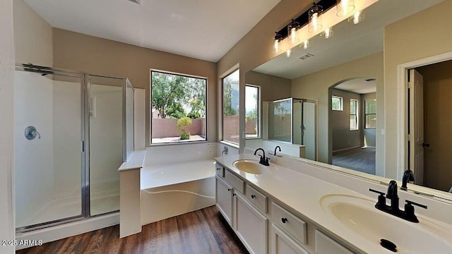 full bath featuring a garden tub, a sink, a stall shower, and wood finished floors