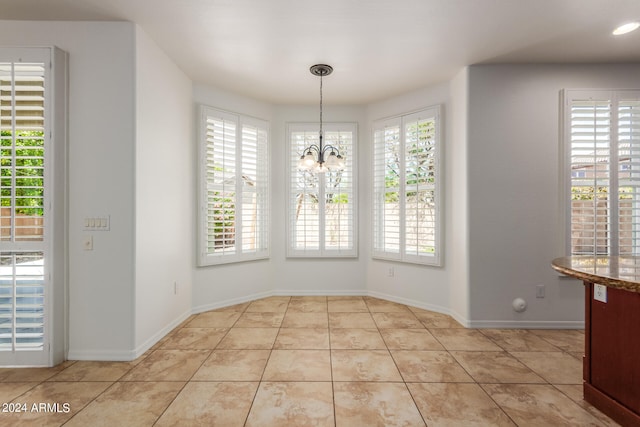 unfurnished dining area with a healthy amount of sunlight, a notable chandelier, and light tile patterned floors