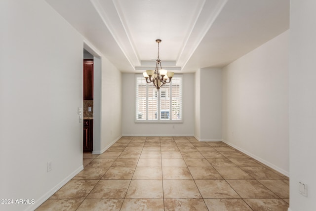 unfurnished room with light tile patterned floors, an inviting chandelier, and a raised ceiling