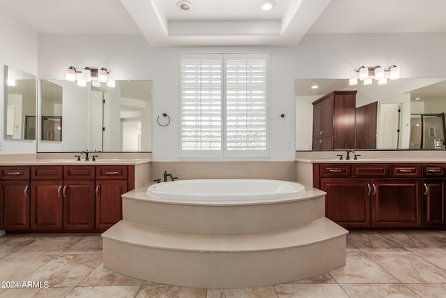 bathroom featuring plus walk in shower, a raised ceiling, and vanity